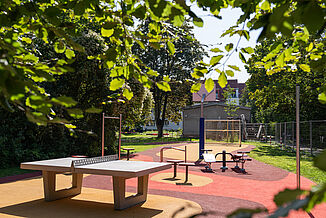 Accessible REGUPOL Play Area in Berlin-Steglitz-Zehlendorf Accessible playground in Berlin-Steglitz-Zehlendorf with REGUPOL impact-absorbing safety surfacing, fitness equipment, table tennis facilities, and an inclusive play and recreation area for children, families, and adults.
