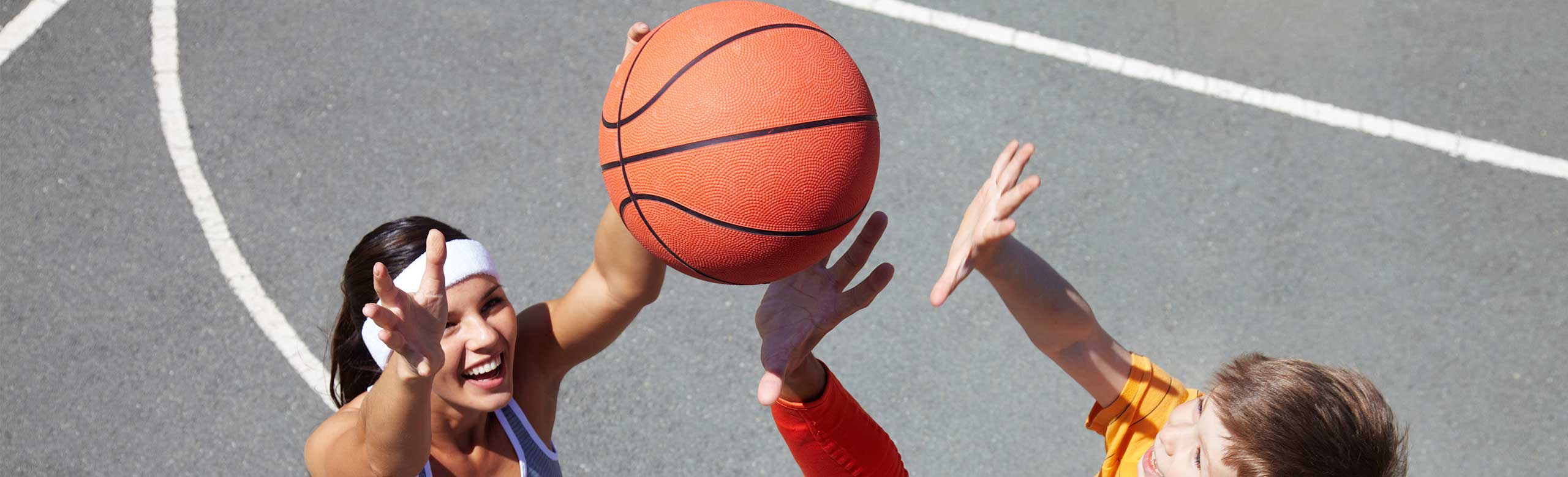 Athletes play basketball on a REGUPOL multicourt DL court - two-layer, in-situ installed sports flooring for multifunctional outdoor playing surfaces without seams