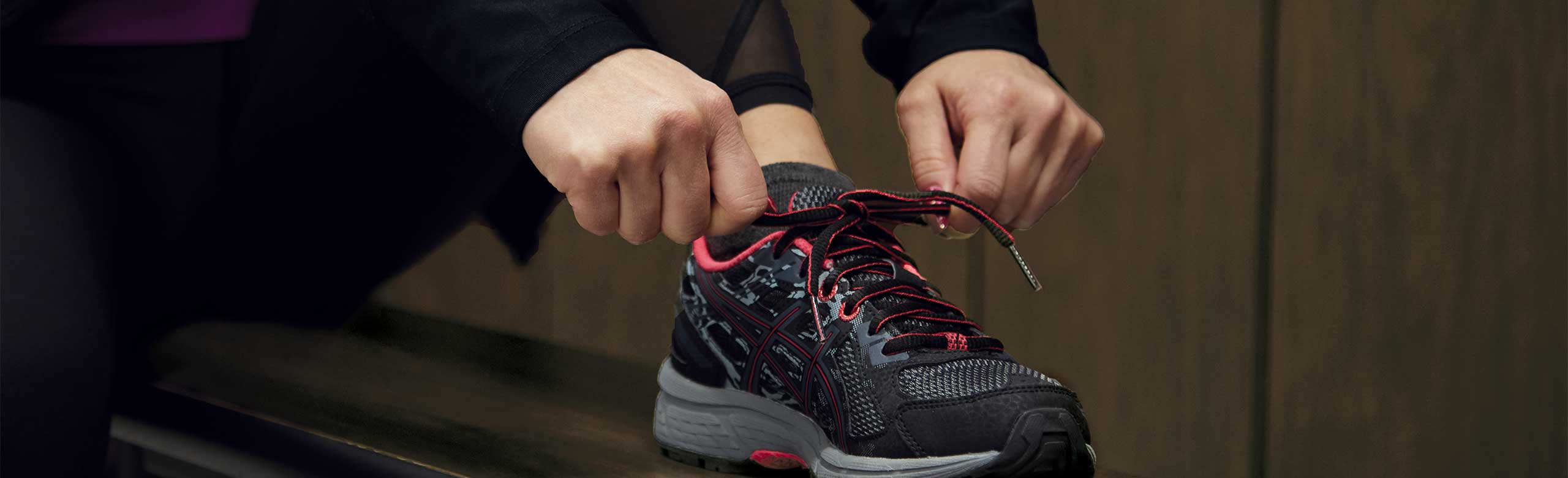 Osoba wiąże but na ławce w przebieralni.