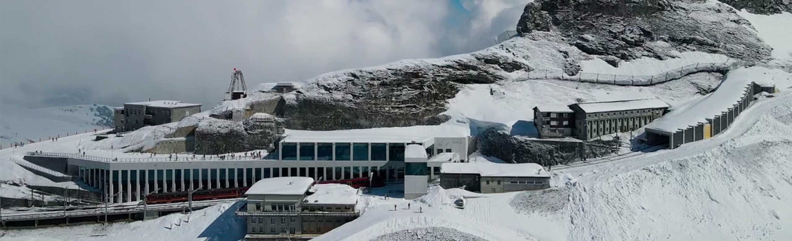 Widok z zewnątrz górskiej stacji kolejowej. Stacja górska znajduje się na górze. Góra i stacja górska są pokryte śniegiem.