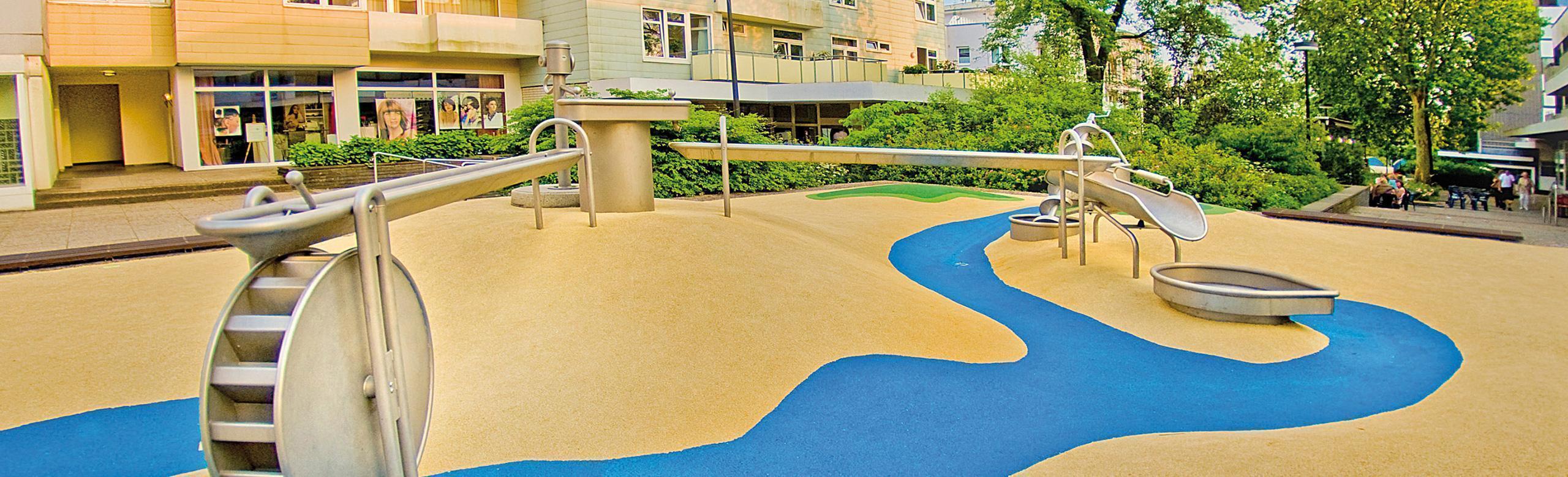 Barrier-free water playground with non-slip, water-permeable REGUPOL playfix aqua safety flooring, complete with interactive water elements.